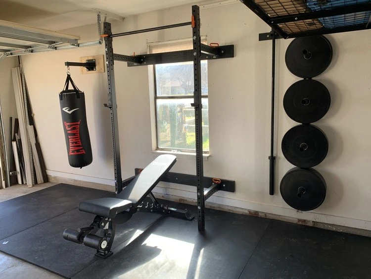 Punching bag, squat rack, and weights inside of a custom-built garage gym.