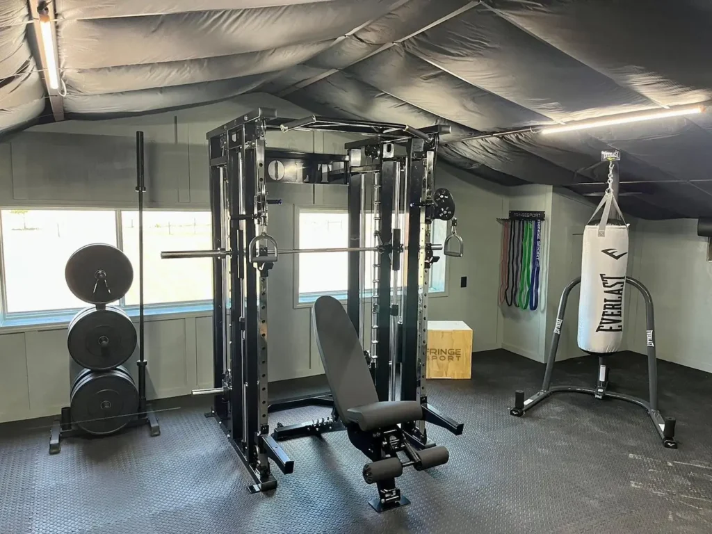Custom garage gym setup with a punching bag, squat rack, and weights.
