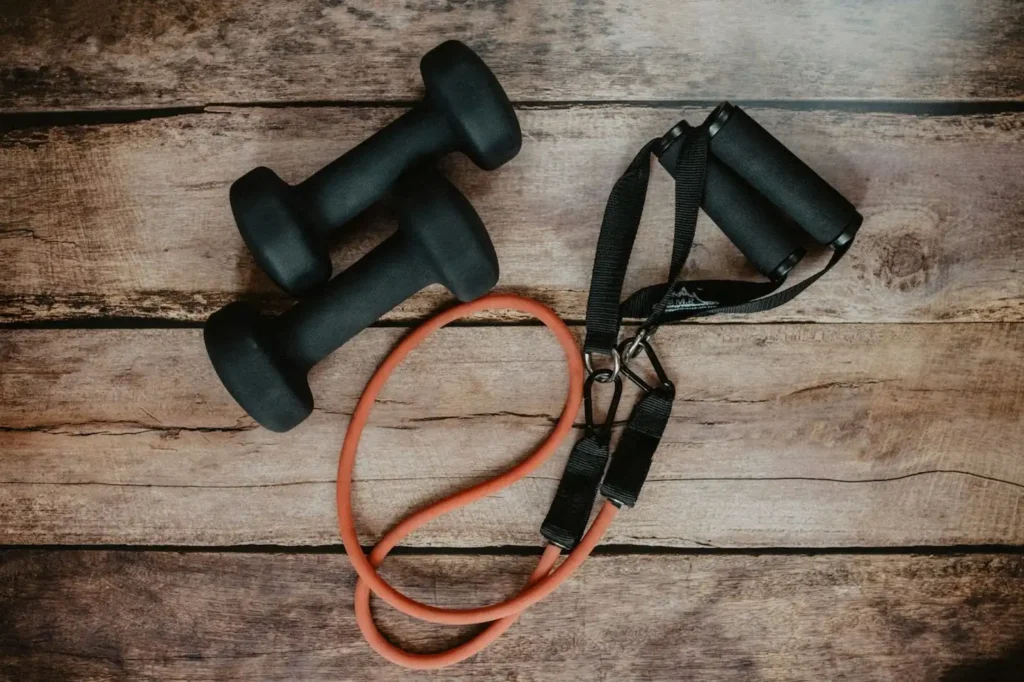 Two dumbbells and a resistance band on a wooden floor.