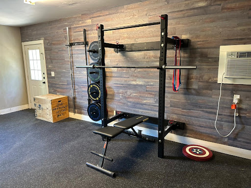 A custom gym with a bench press exercise station, a wooden workout box, and an AC system.